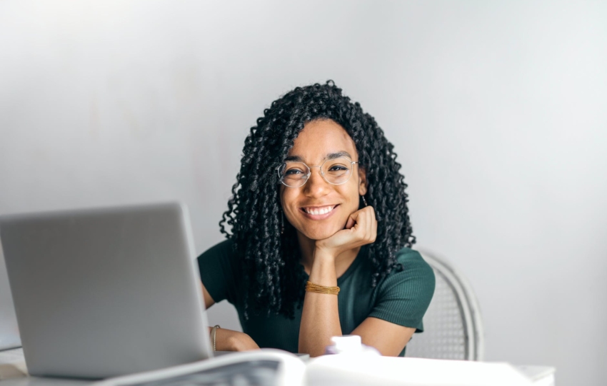 happy ethnic woman sitting at table with laptop