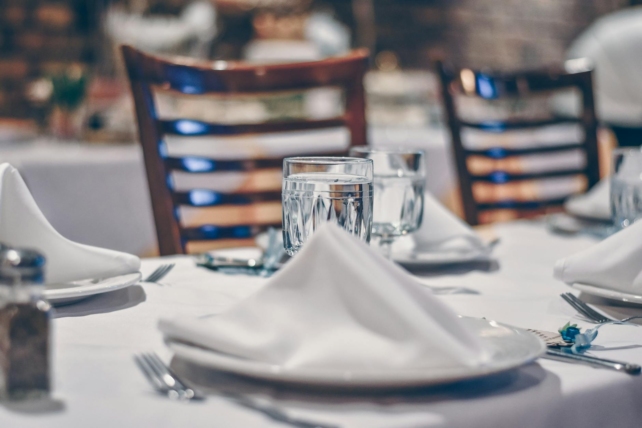 depth of field photo of clear drinking glass on white table near plate